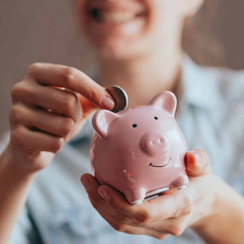female putting a coin into a piggy bank